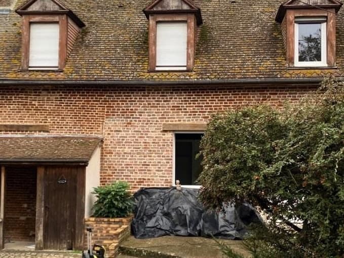 Longère en brique à trois lucarnes, couverture en tuile plate envahie par la mousse