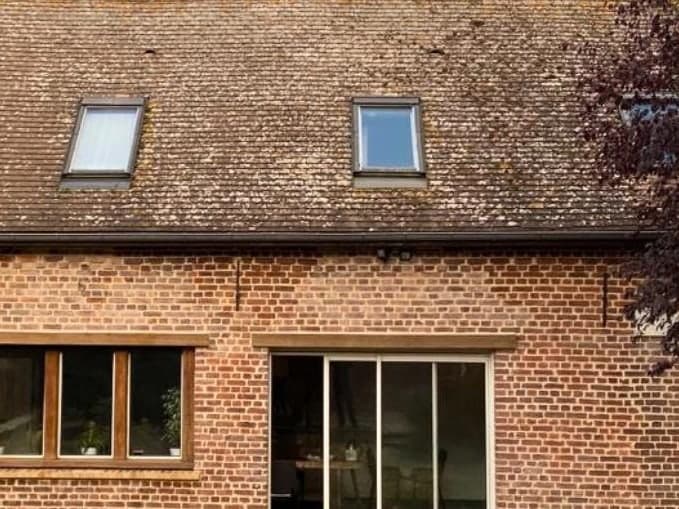 Maison en brique avec deux fenêtres de toit, couverture encrassée