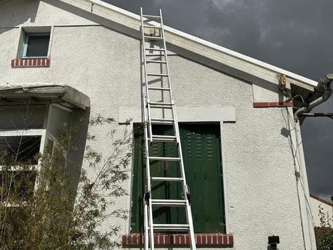 Pignon enduit dont la rive est déposée, échelle appuyée contre la façade